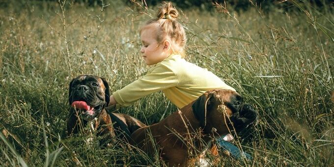 kislány játszik egy kutyussal a zöld fűben
